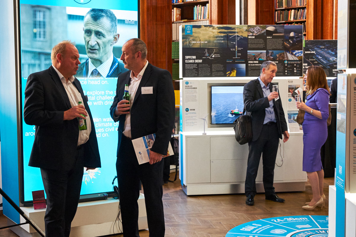guests at a London event standing in front of a screen